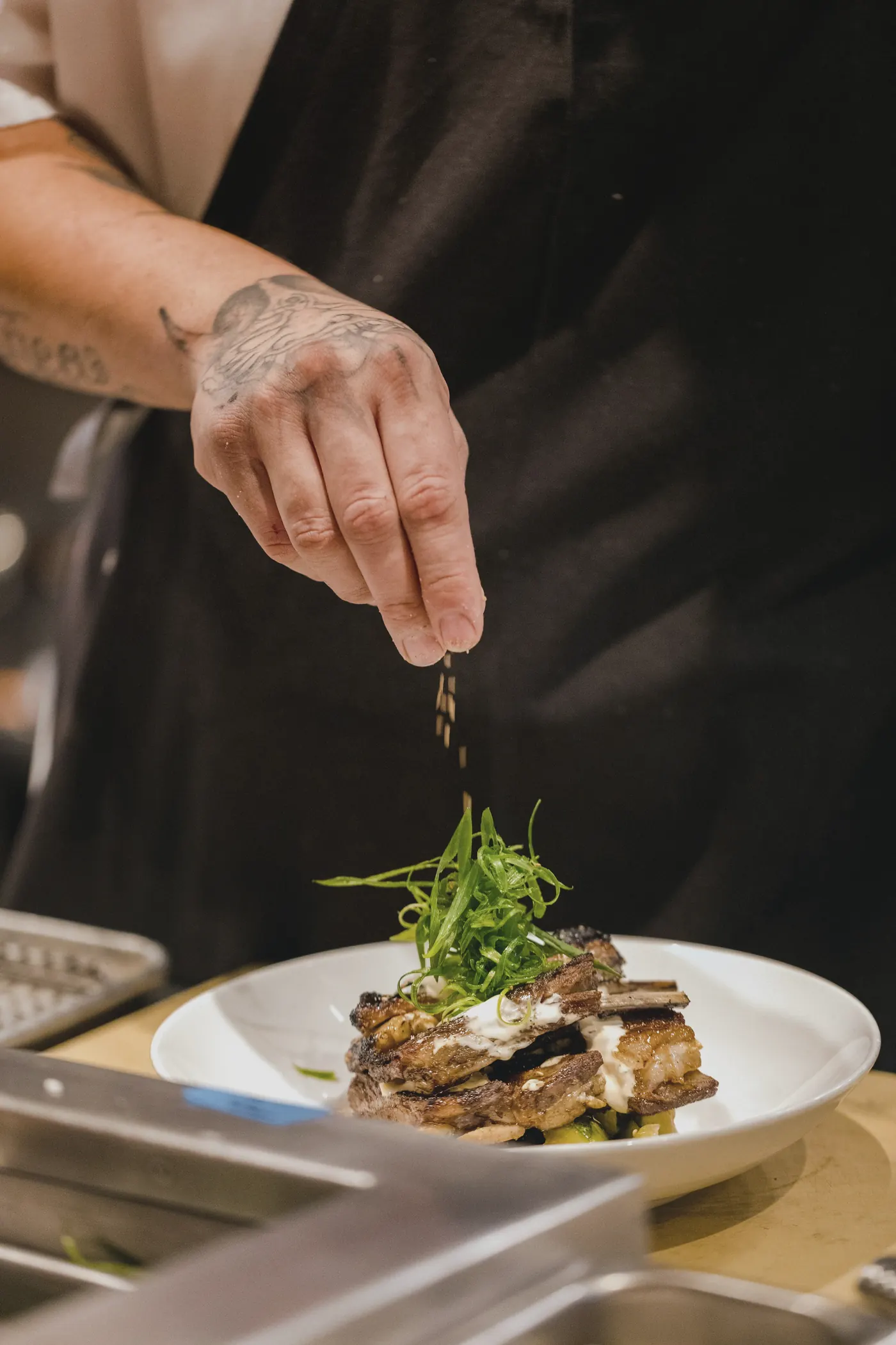 A chef finishing a plate at the pass